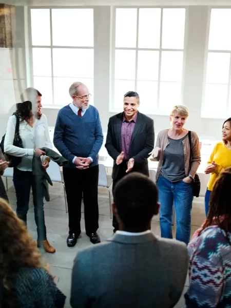 Members of an office gather around to participate in team building activities to strengthen their team