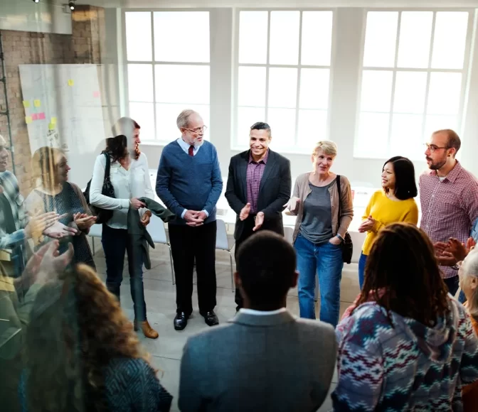 Members of an office gather around to participate in team building activities to strengthen their team