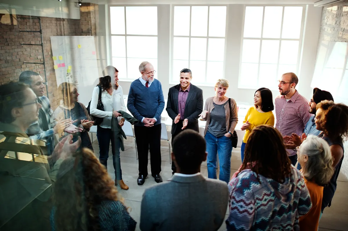 Members of an office gather around to participate in team building activities to strengthen their team