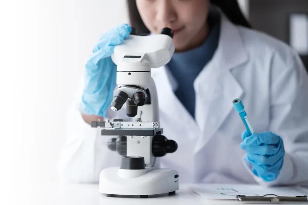 A woman looks through a microscope